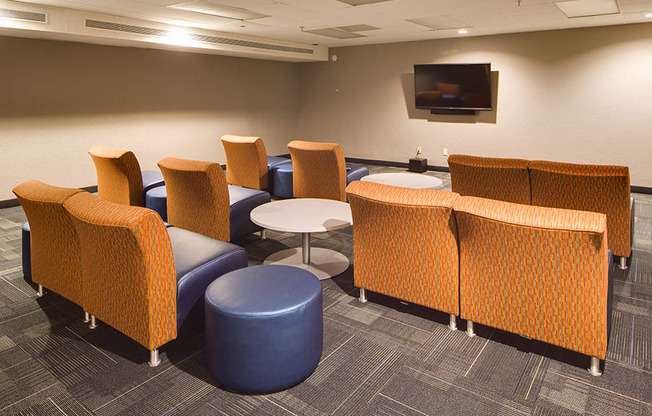 media room with three rows of orange chairs looking towards TV mounted on the wall