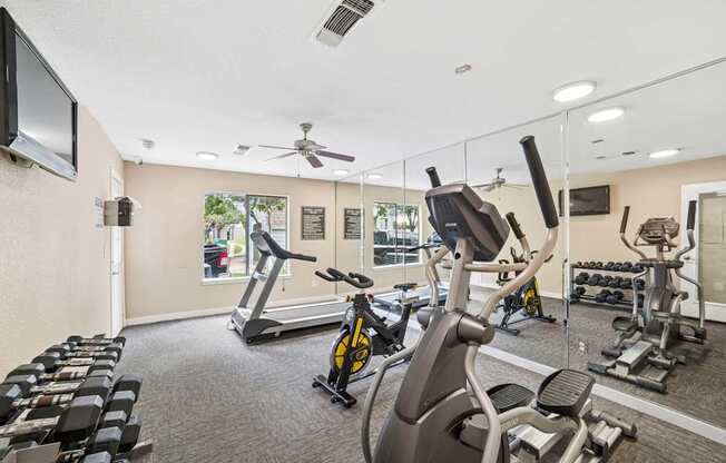 A gym with a variety of exercise equipment including treadmills, stationary bikes, and weight machines.