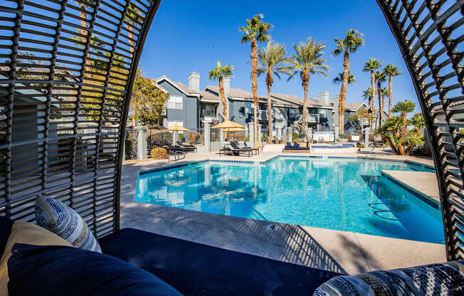 A pool surrounded by palm trees and a patio area.