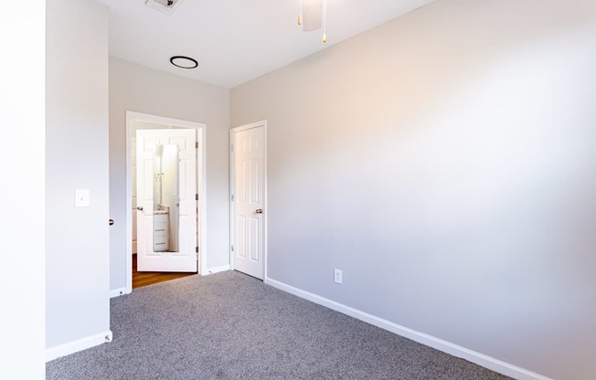 A room with a carpeted floor and a doorway leading to another room.