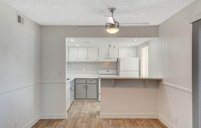 A kitchen with white cabinets and a wooden floor.