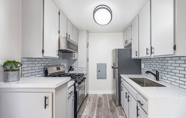 Tiled kitchen with stainless steel fridge, oven, and miocrowave.