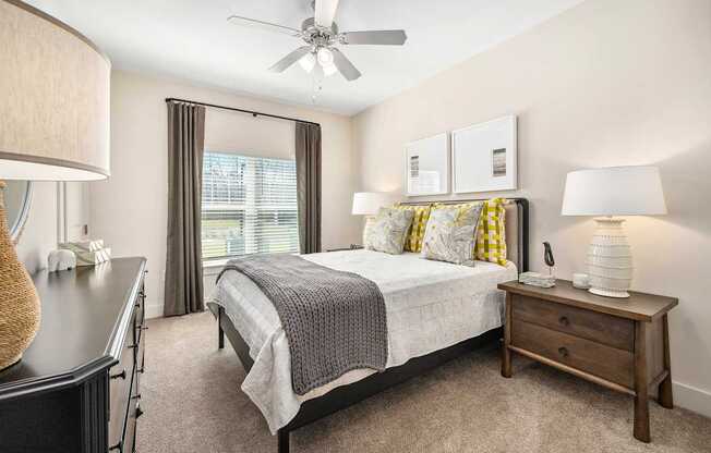 A bedroom with a bed, nightstand, and a ceiling fan.