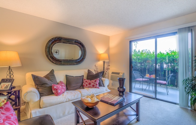 A living room with a white couch, a coffee table, and a large mirror on the wall.