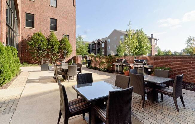 a patio with tables and chairs in front of a brick building