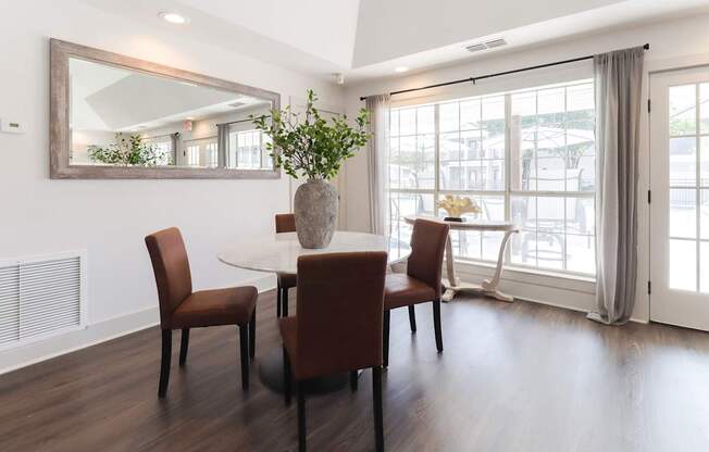 A dining room with a white table and brown chairs.