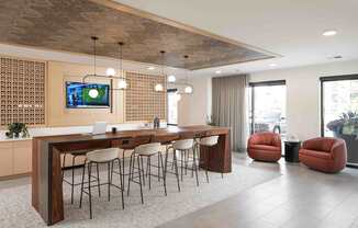 A modern office space with a long wooden table and chairs, a television on the wall, and a view of the city outside the windows.