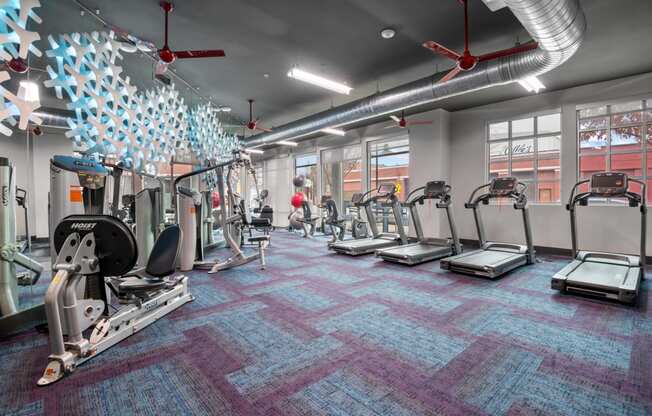 a gym with treadmills and other exercise equipment in a building with windows at South Side Flats, Dallas, 75215