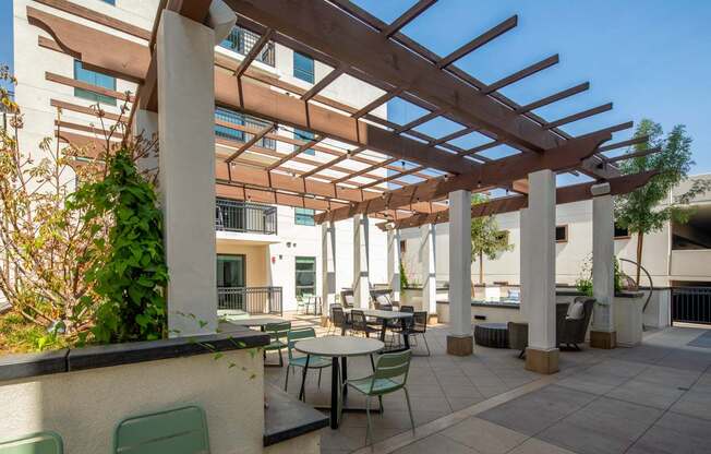A patio with a table and chairs under a wooden pergola.