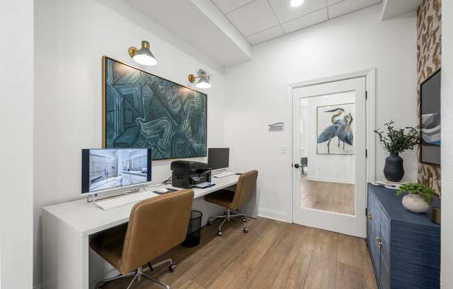 a community office with two computers and a painting on the wall