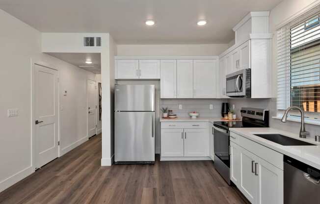 a renovated kitchen with white cabinets and stainless steel appliances