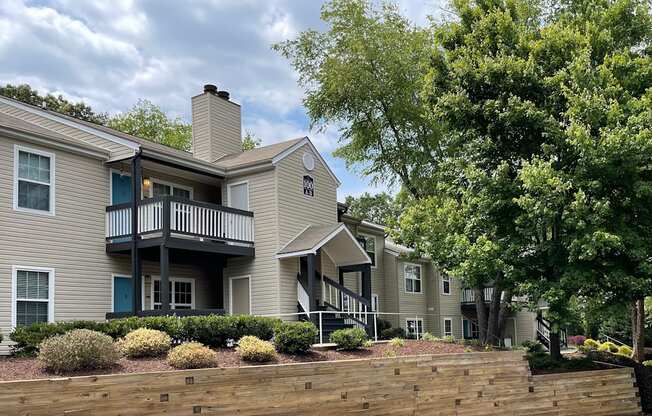 an exterior view of an apartment complex with a stone retaining wall and trees