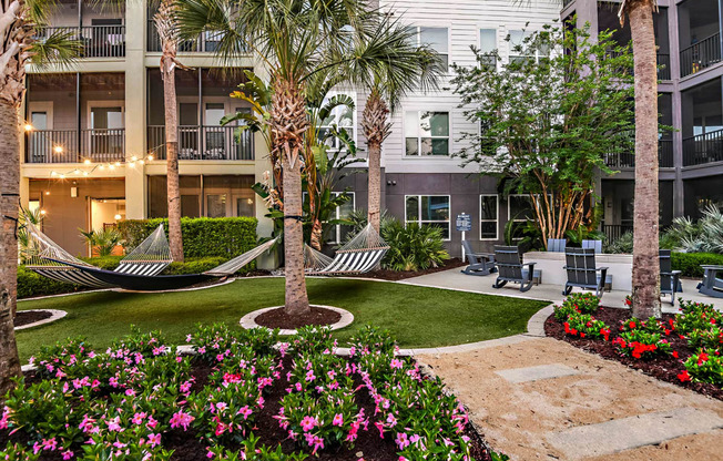 a courtyard with hammocks and flowers in an apartment building