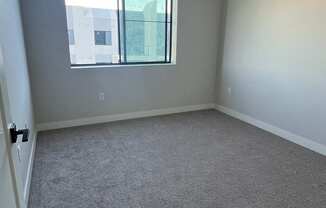 an empty room with a window and carpet