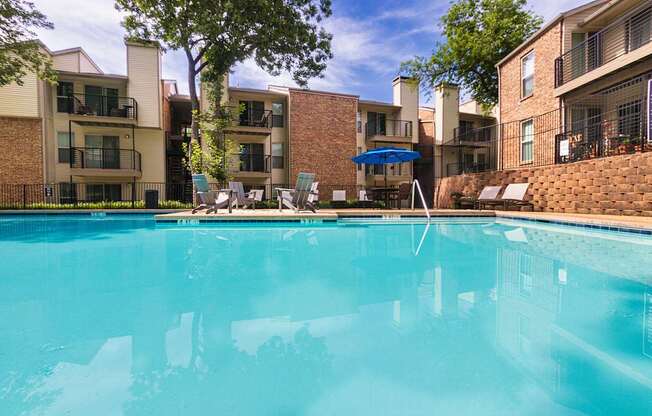 A swimming pool in front of apartment buildings at Canyon Creek Apartments in the Dallas Midtown neighborhood of Dallas, TX.