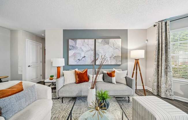 A living room with a grey couch and a large abstract painting on the wall.