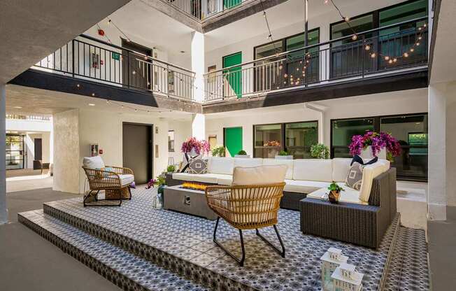 A patio with a table and chairs is surrounded by a balcony.