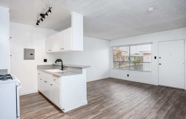 an empty kitchen with white cabinets and a window