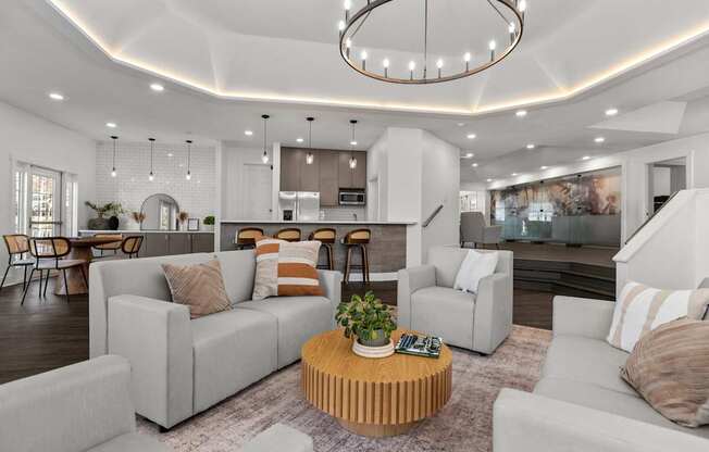 A modern living room with a large grey sofa, a wooden coffee table, and a chandelier.