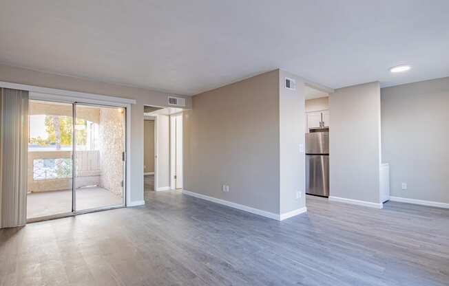 an empty living room with a sliding glass door to a patio  at Sofia Apartments, Arizona