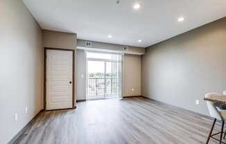 an empty living room with a door to a balcony