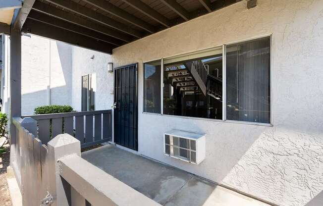 A white house with a black gate and a concrete staircase.