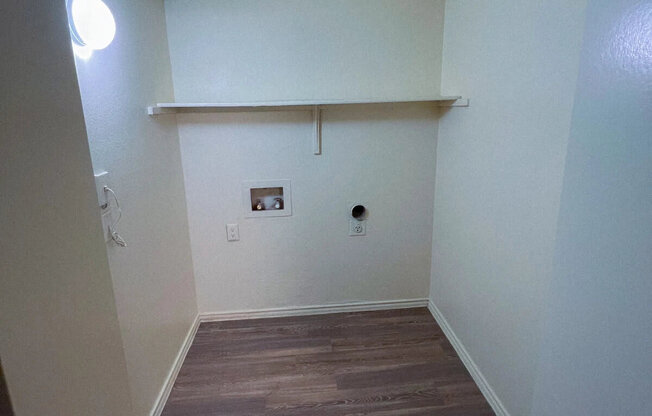 a room with a wood floor and white walls and a white shelf