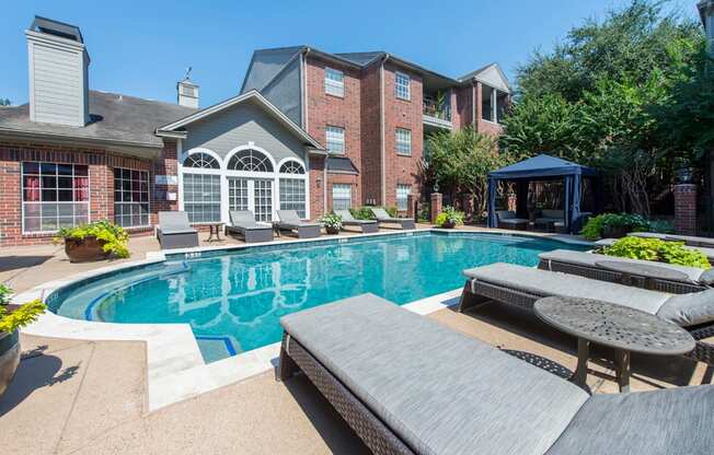 A swimming pool with lounge chairs at The Inverness Apartments in Houston, TX