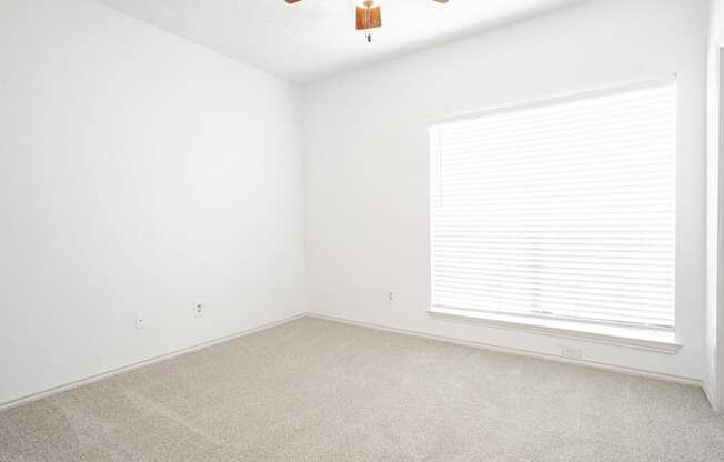 an empty room with a window and a ceiling fan