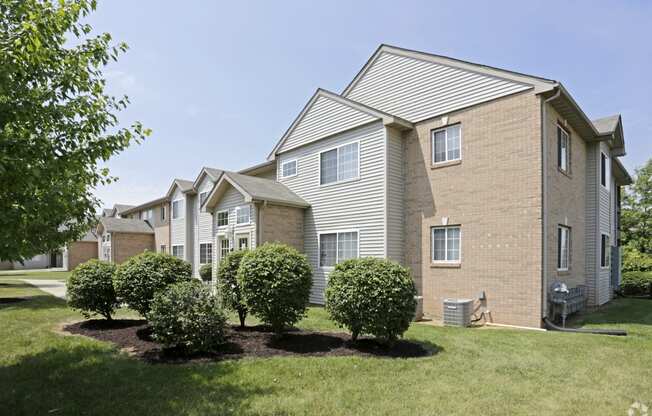 the view of a brick apartment building with lawns and trees