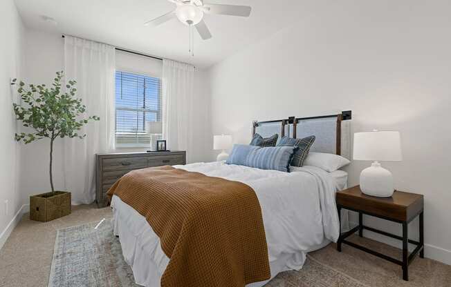 A bedroom with a bed, nightstand, and a plant.