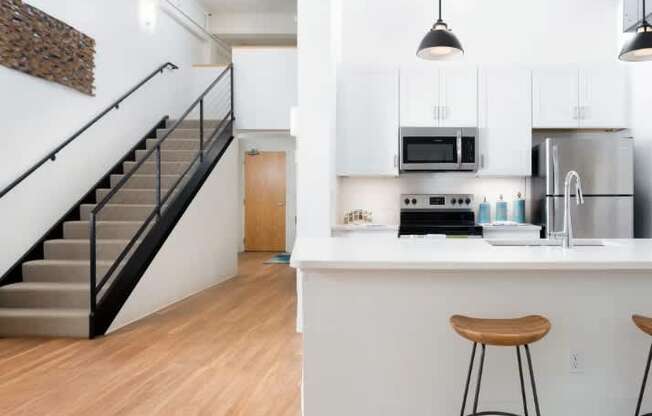 A kitchen with white cabinets and a bar area with stools.