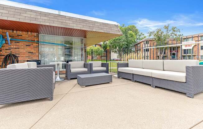 A patio with grey furniture and a brick building in the background.