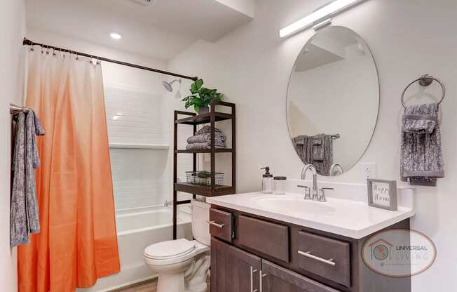 A bathroom with an orange shower curtain and a white toilet and a sink.