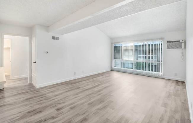 A room with wooden flooring and a window with blinds.