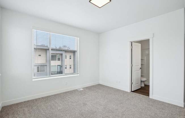 A room with a carpeted floor and a window with blinds.