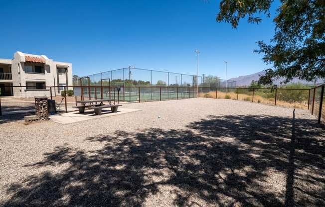 a picnic area in a park next to a tennis court and a building