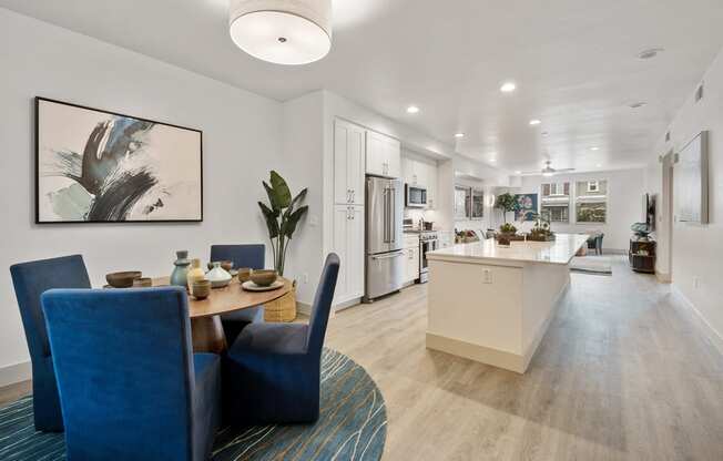 a living room and kitchen area with blue chairs and a table