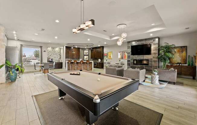 A pool table is in the middle of a room with a fireplace and a TV.