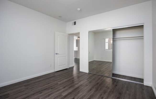 a bedroom with white walls and hardwood floors