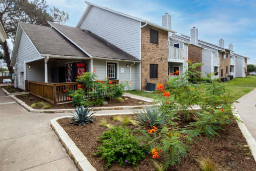 the front yard of a house with flowers and a sidewalk