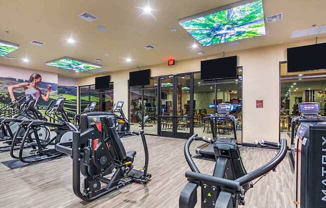 A gym with a variety of exercise equipment including treadmills, stationary bikes, and weight machines.