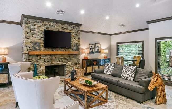 A living room with a stone fireplace and a grey couch at Ridge Crossings Apartments, Hoover, 35244