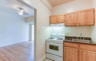 kitchen with wood cabinetry, gas range and view of living area at twin oaks apartments columbia heights washington dc