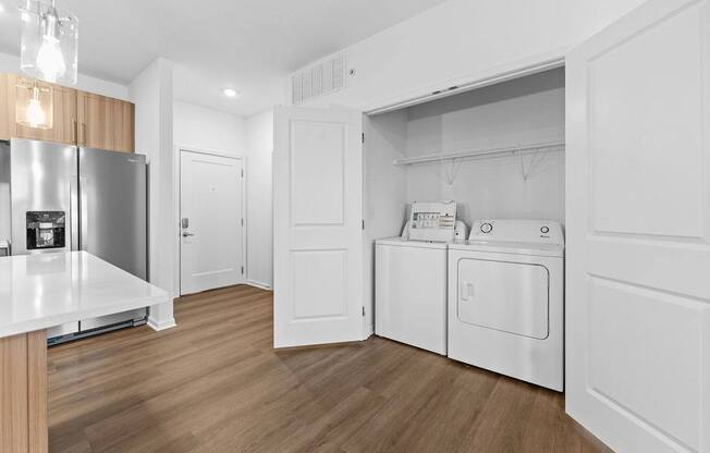 A modern kitchen with a refrigerator, oven, and washing machine.