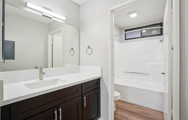 A bathroom with a white sink and brown cabinets.