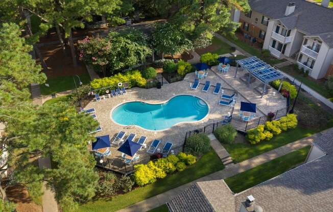 an aerial view of a resort style pool with lounge chairs and umbrellas