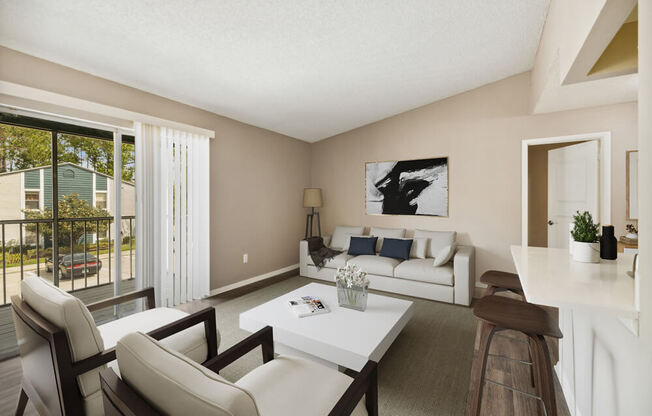 Living room with a white couch and a white coffee table in front of a sliding glass at Vue at Baymeadows Apartments in Jacksonville, Florida