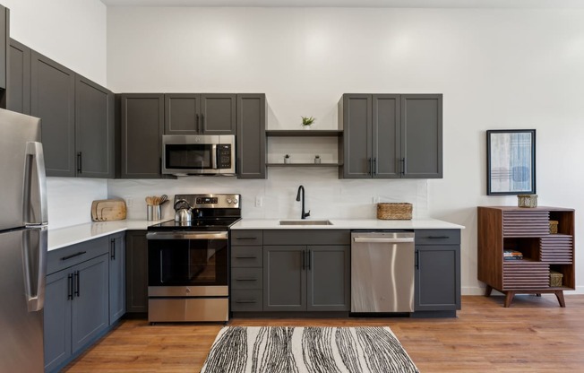 a kitchen with gray cabinets and stainless steel appliances