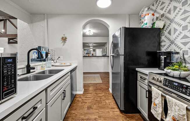 A kitchen with a black fridge and stove top oven.